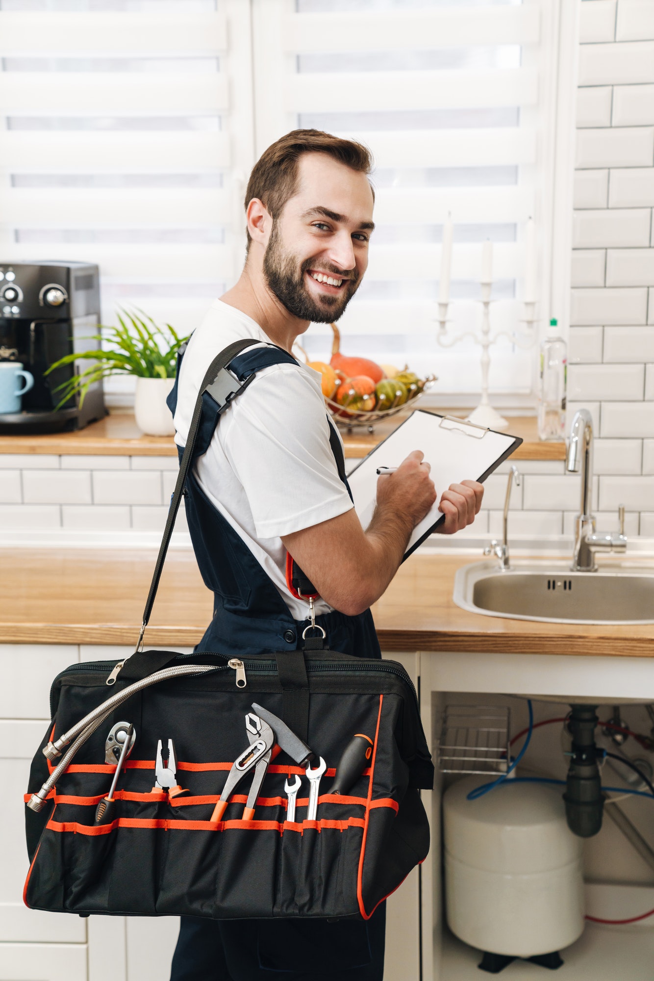 Image of plumber man with equipment and clipboard working in apartment